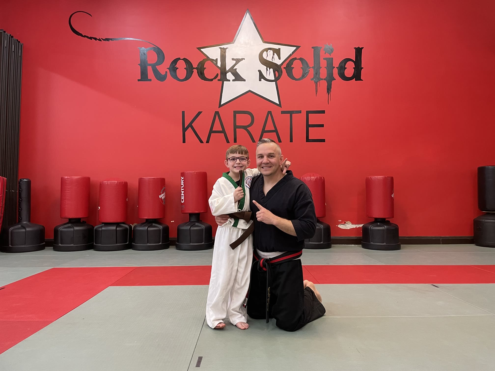 Lee Sandt with his son in front of the Rock Solid Karate wall